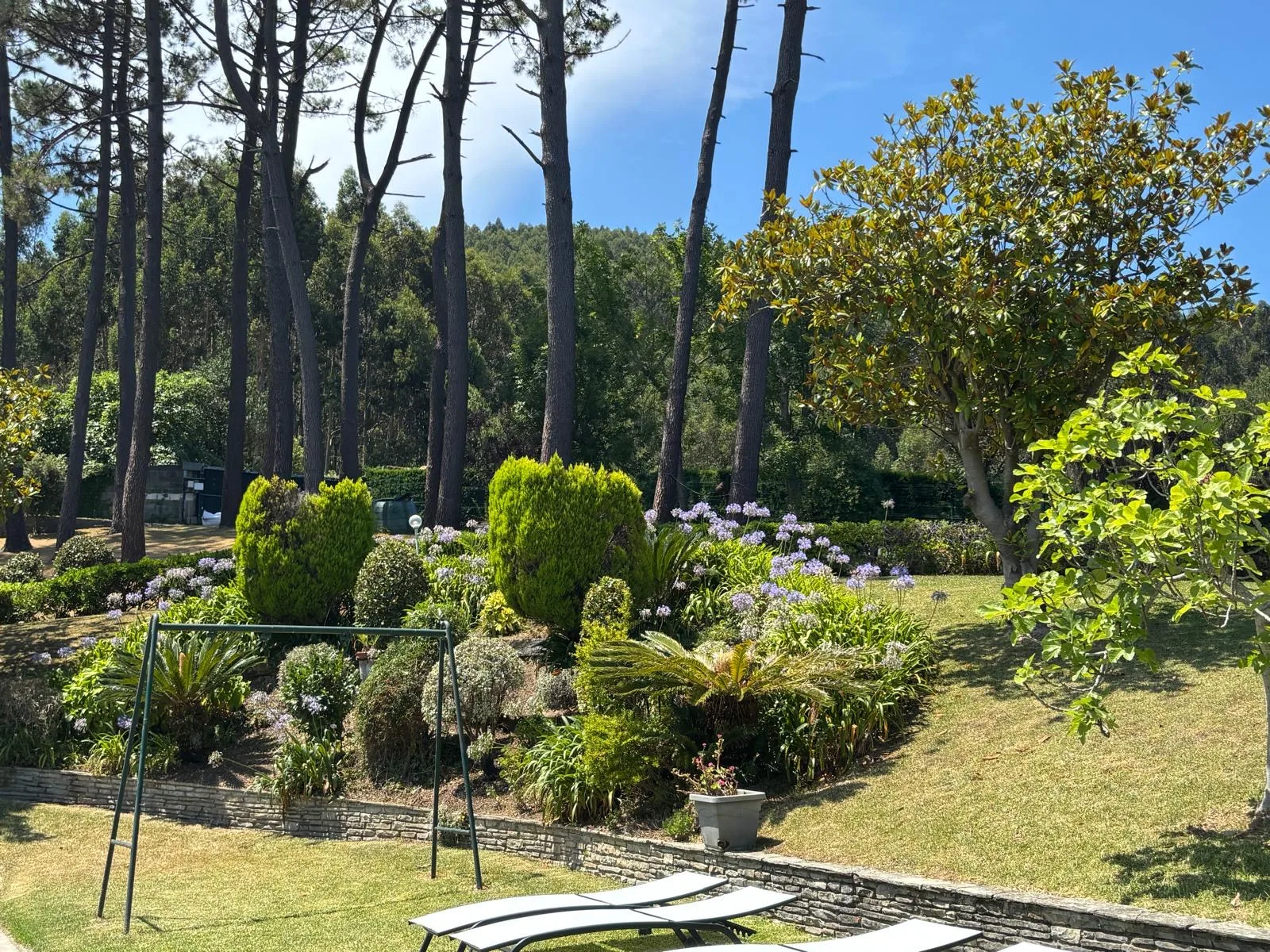 Jardín arbolado y zona de descanso exterior del Hotel Arresi en Armintza